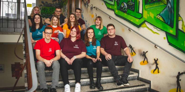 teamfoto von zeichen gegen mobbing auf einer schultreppe sitzend