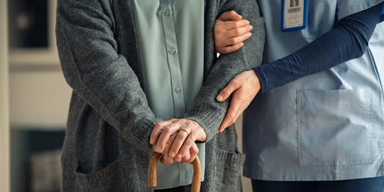 Person mit Spazierstock wird gestützt