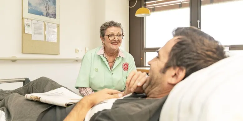 Grüne Damen besucht kanrken Mann an seinem Bett im Krankenhaus